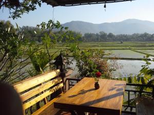 a wooden bench sitting on a table overlooking a river at Jamjuree Garden in Ban Thung Ma Nieo