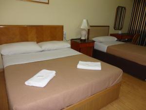 two beds in a hotel room with towels on them at Pristine Hotel in Rawang