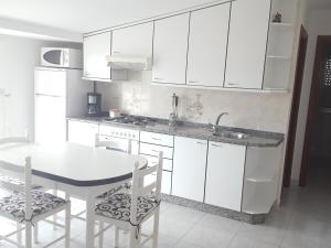a kitchen with white cabinets and a table and chairs at Casa Artemia in Sanxenxo