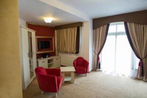 a hotel room with red chairs and a table and window at Pensiunea Cristina in Craiova