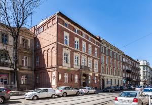 a large brick building with cars parked on a street at Hotel Maksymilian in Krakow
