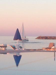 ein Boot im Wasser mit einem Segelboot im Ozean in der Unterkunft Pyrgos Blue in Malia