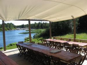 a wooden table and chairs on a deck next to a river at Koitelin Residenssi in Oulu