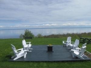 a group of white chairs sitting on a wooden deck at Gite la Maison Rochefort in Baie-Sainte-Catherine