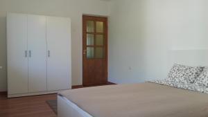 a white bedroom with a bed and a door at Trakai White Apartments in Trakai