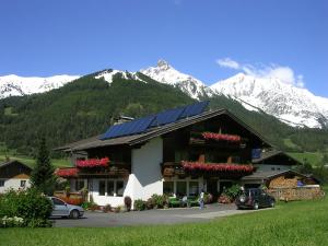 a building with solar panels on it with mountains in the background at Haus Bergheimat in Kals am Großglockner
