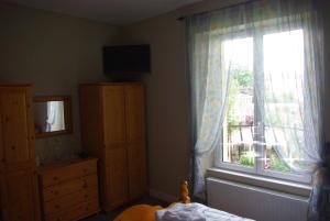 Schlafzimmer mit einem Fenster mit einem TV und einer Kommode in der Unterkunft La Maison Celtique in Saint-Nicolas-du-Pélem