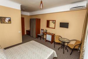 Hotel Edem في ألوشتا: غرفة فندقية بسرير وطاولة وكراسي