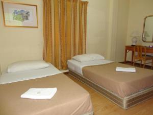 two beds in a room with a table and a desk at Pristine Hotel in Rawang
