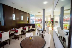 a dining room with tables and white chairs at Hotel Necof in Rosario
