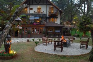 a house with chairs and a fire in front of it at Pousada Da Pedra in Campos do Jordão