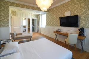 a bedroom with a bed and a desk and a television at Suite Milano Duomo in Milan