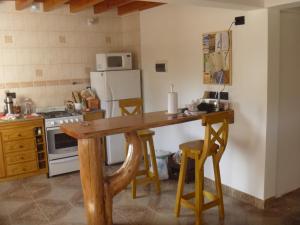 a kitchen with a wooden table and a refrigerator at Cabaña Lecalau in Lago Puelo