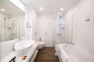 a bathroom with a sink and a tub and a toilet at Thassos Grand Resort in Alyki