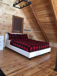 Chalet du Versant Nord في Saint-David-de-Falardeau: سرير في غرفة ذات سقف خشبي