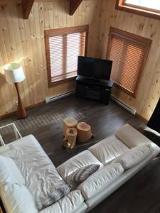 a living room with a white couch and a flat screen tv at Chalet du Versant Nord in Saint-David-de-Falardeau