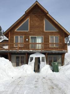 a log house with snow in front of it at Chalet du Versant Nord in Saint-David-de-Falardeau