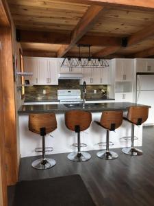 a kitchen with a counter with four bar stools at Chalet du Versant Nord in Saint-David-de-Falardeau