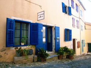 a building with blue shutters and plants in front of it at Apartments Galerija Motovun in Motovun
