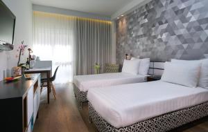 a hotel room with two beds and a desk at Prima Tel Aviv Hotel in Tel Aviv