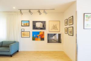 a living room with a blue chair and pictures on the wall at Prima Tel Aviv Hotel in Tel Aviv