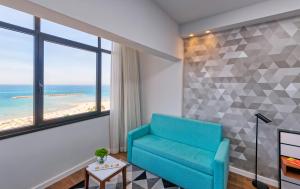 a living room with a blue chair and a view of the beach at Prima Tel Aviv Hotel in Tel Aviv