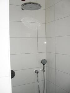 a shower with a white tile wall and a shower head at Alte Mühle Kaisersdorf in Kaisersdorf