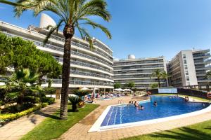 uma piscina de resort com uma palmeira e edifícios em Central park Blanes em Blanes