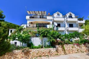 Un edificio blanco con un muro de piedra delante. en Apartments Petrovac, en Zavala