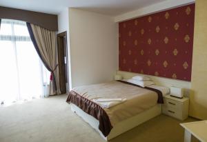 a bedroom with a bed and a red wall at Pensiunea Cristina in Craiova
