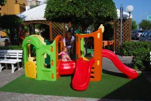 Ein kleines Mädchen spielt auf einem Spielplatz mit einem Zug in der Unterkunft Hotel Perla in Senigallia