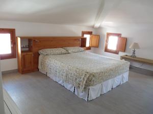 a bedroom with a bed and two windows at Sa Lluna in Es Mercadal