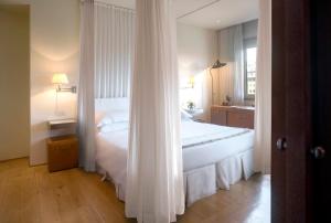 Un dormitorio con una gran cama blanca y una ventana en Hotel Continentale - Lungarno Collection, en Florencia