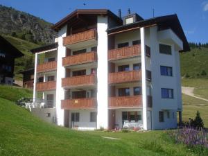 ein weißes Apartmenthaus mit Balkon auf einem Hügel in der Unterkunft Apartment Weisshorn in Riederalp