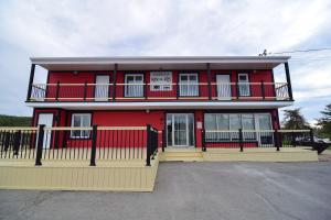 een rood gebouw met een hek ervoor bij Mon Coin de Pays in Sacré-Coeur-Saguenay