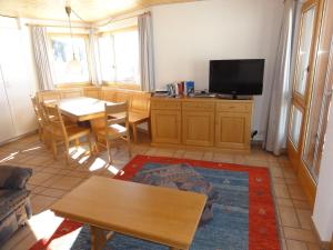 ein Wohnzimmer mit einem Tisch und einem TV in der Unterkunft Apartment Weisshorn in Riederalp