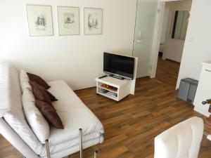 a living room with a white couch and a tv at meine-nordsee-fewo in Esens