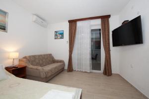 a room with a couch and a chair and a television at Apartments Šarić in Baška Voda