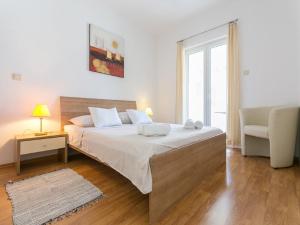a bedroom with a bed and a chair and a window at Apartments Tomy & Domy in Dubrovnik