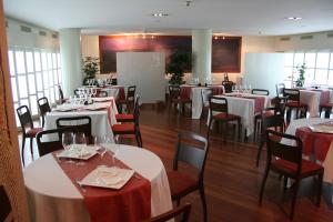 un comedor con mesas blancas y sillas rojas en Hotel Villa De Betanzos, en Betanzos