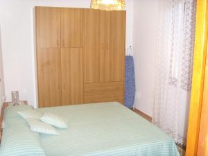 1 dormitorio con 1 cama y armario de madera en villletta indipendente a 300 metri dal mare, en Solanas