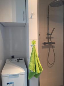 y baño con ducha, aseo y toalla verde. en Apartament, en Kołobrzeg