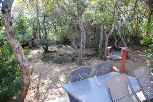 a table and chairs with a grill in the woods at Residence Ribellinu in Pianottoli-Caldarello