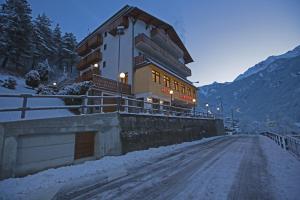 un edificio en un puente sobre una carretera cubierta de nieve en Hotel Biancospino, en Lanzada