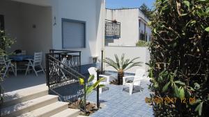 a patio with two white chairs and a plant at La sterlizia in Mondello