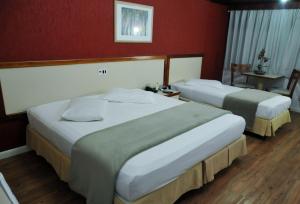 two beds in a hotel room with red walls at Inter Plaza Hotel in Sorocaba