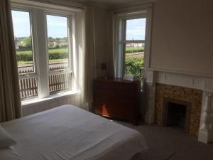 a bedroom with a bed and two windows and a fireplace at Ayrshire cottage in Kilmarnock