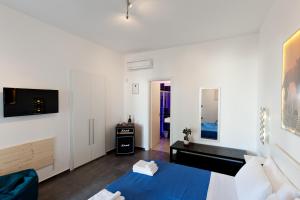 Dieses weiße Zimmer verfügt über ein blaues Bett und einen TV. in der Unterkunft Bed & Blues in Torre Lapillo