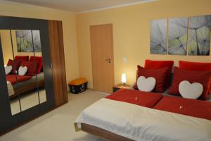 Schlafzimmer mit einem Bett mit roten und weißen Kissen in der Unterkunft Ferienwohnung Domschatz in Naumburg