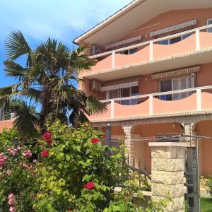 a pink building with a palm tree and flowers at Porta Anna Apartments in Medulin